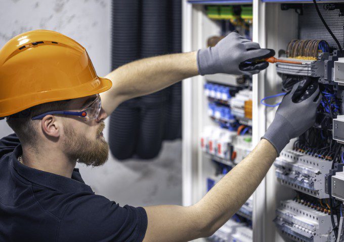 A man in an orange hat and gloves is working on something.
